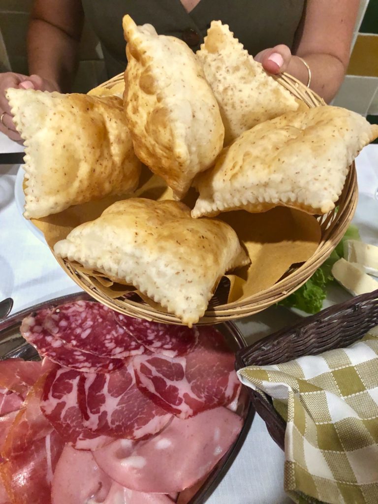Basket of gnocco fritto with a plate of cold cuts