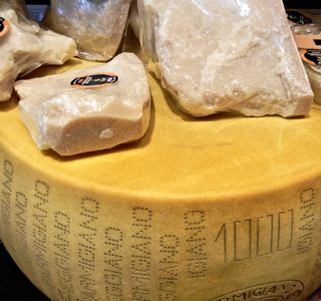 Wheel of Parmigiano-Reggiano with wrapped wedges of cheese on top