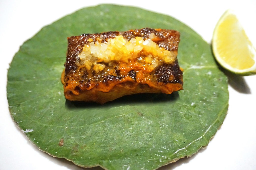 Black cod on an hoja santa leaf tortilla with a lime wedge on the side