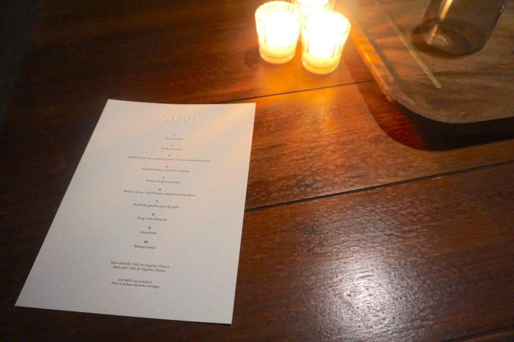 Pujol menu on the table with candles