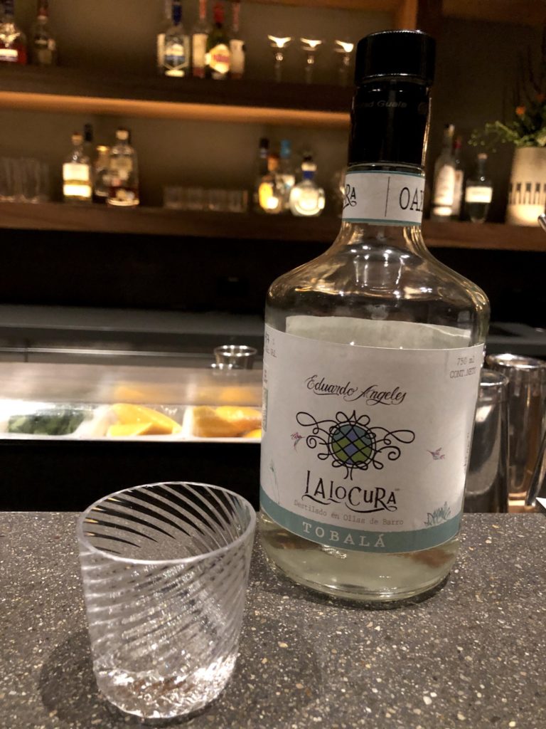 Bottle of mezcal on the bar with a glass