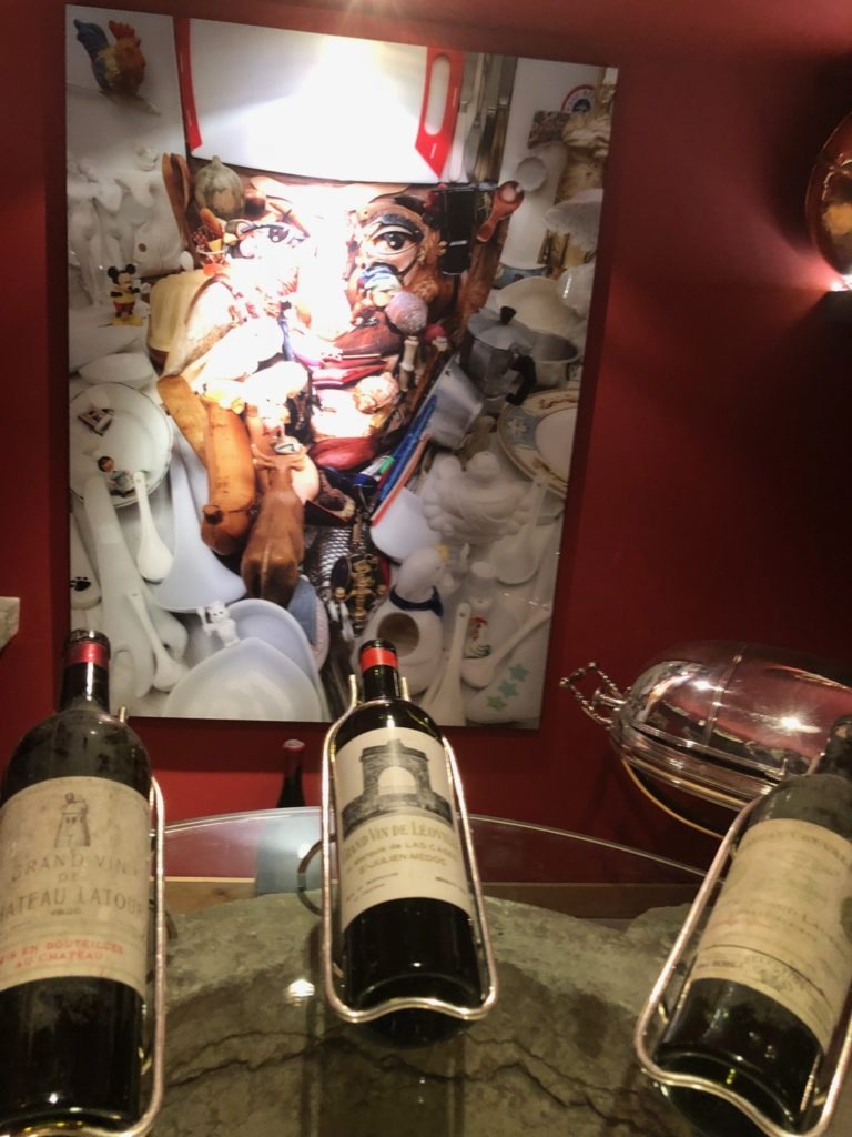 Three wine bottles in the cellar with a mural of Paul Bocuse