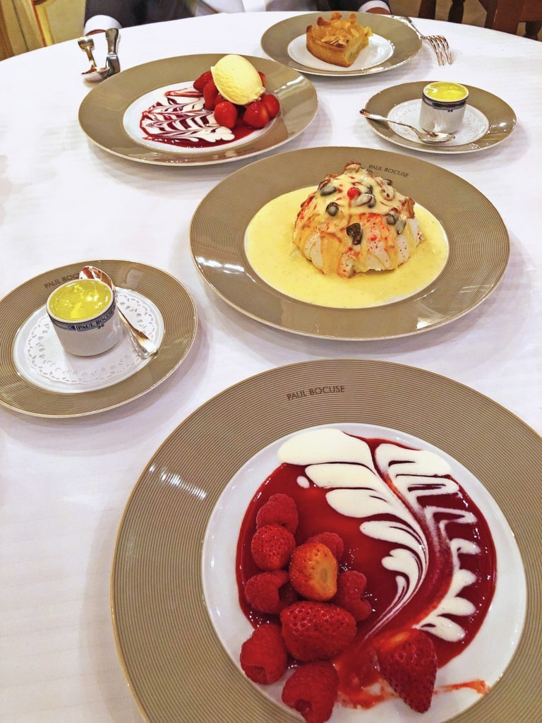 Plate of berries with red and white sauce, plate of meringue, plate of berries, and plate of tarte tartin