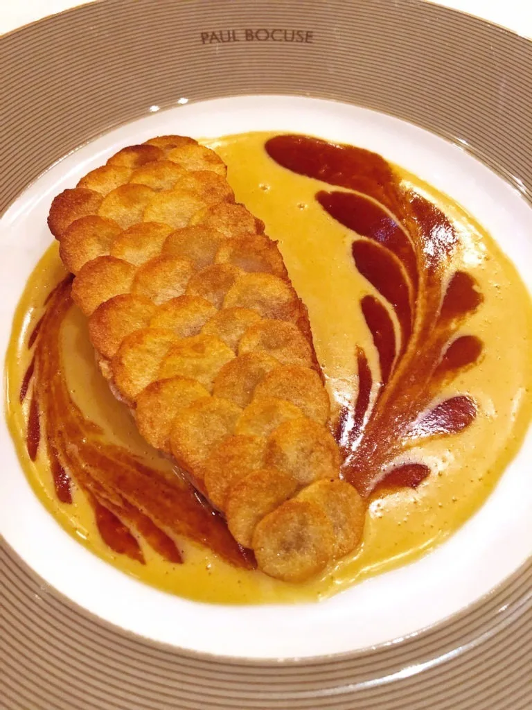 Fish fillet with scales made of crispy potatoes on a mix of two sauces