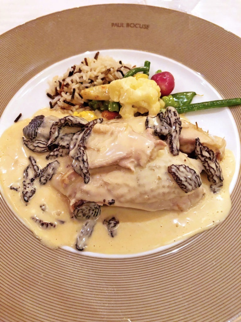 Chicken breast topped with cream sauce with morel mushrooms and rice and vegetables