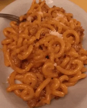 Gramigna being topped with Parmigiano-Reggiano