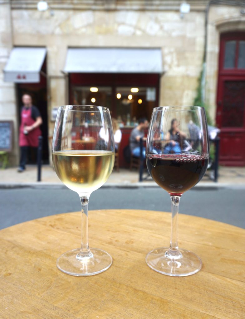 Glasses of white and red wine on a table outside of a restaurant