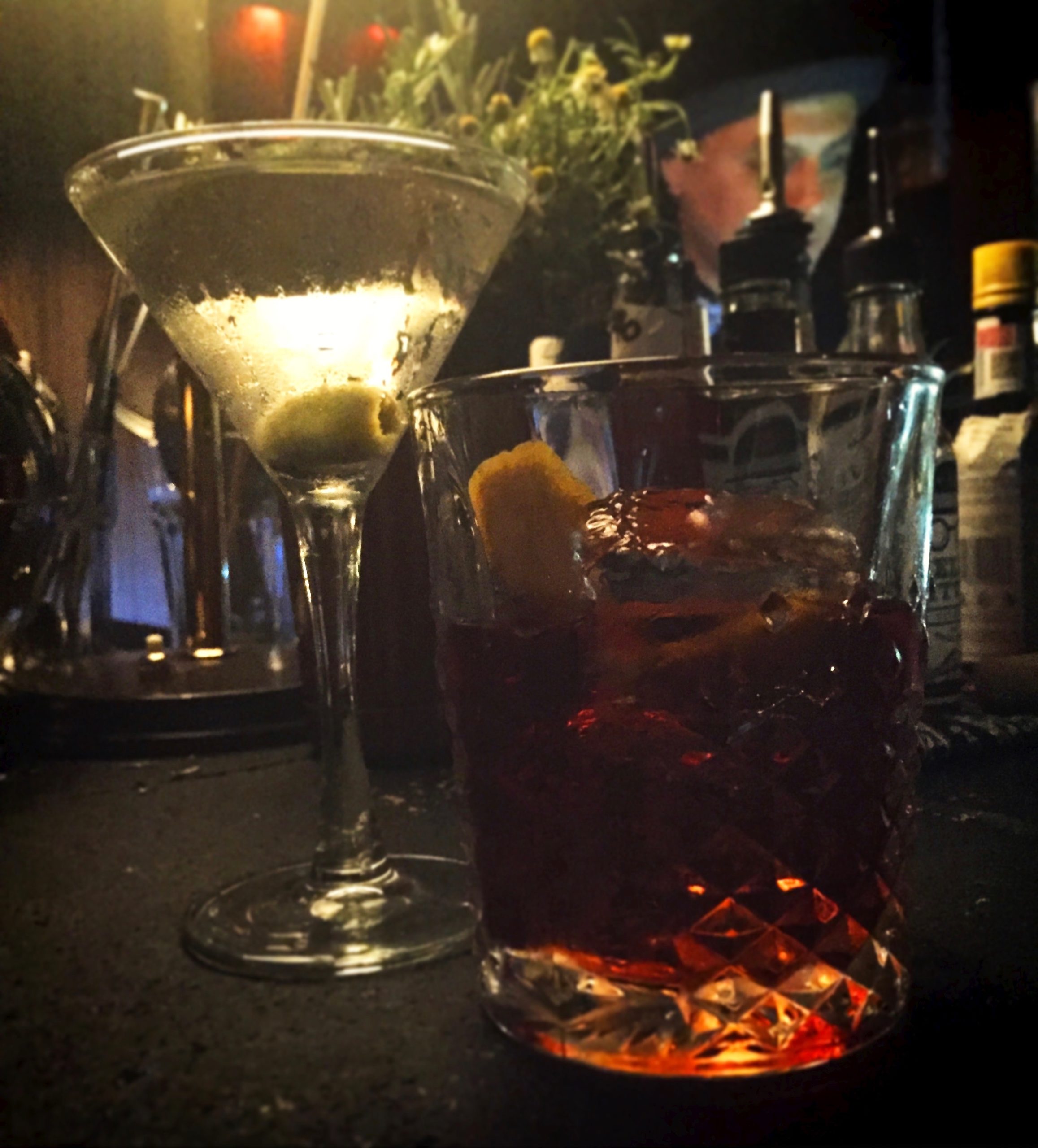 A martini on the left and negroni on the right in a dark bar