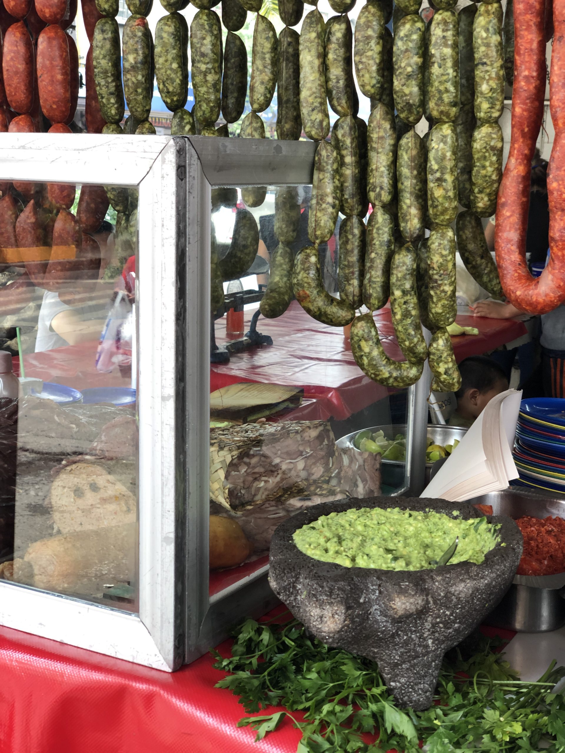 Green chorizo hanging with a bowl of guacamole underneath