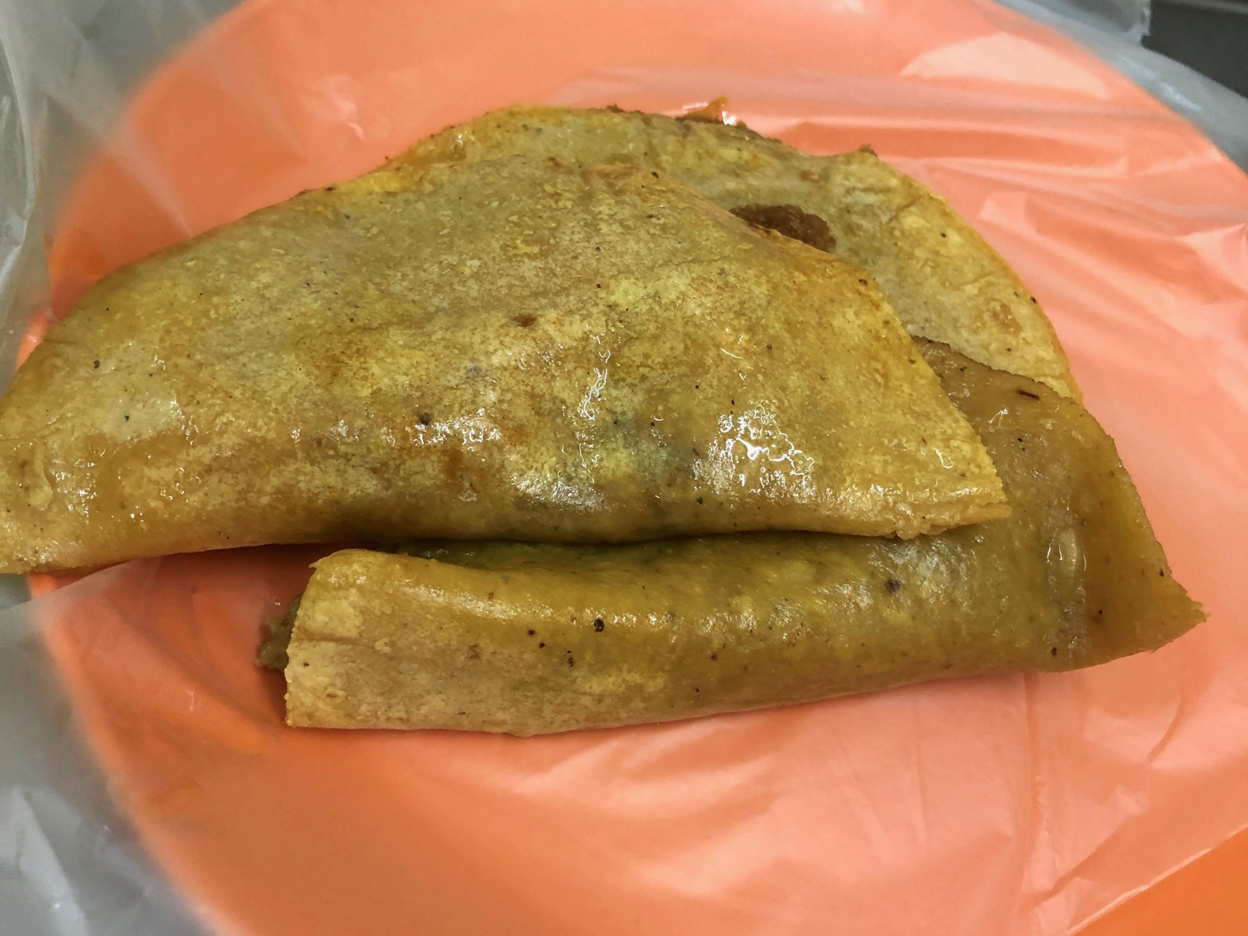 Three tacos de canasta on an orange plate