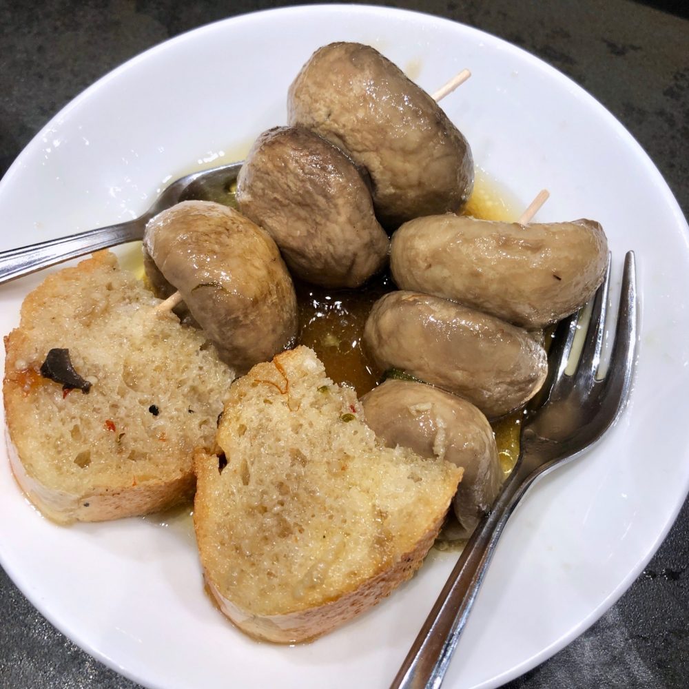 Two skewers with three mushroom caps each and pieces of bread
